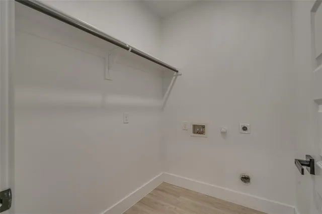 an empty room with wooden floor chandelier fan and windows