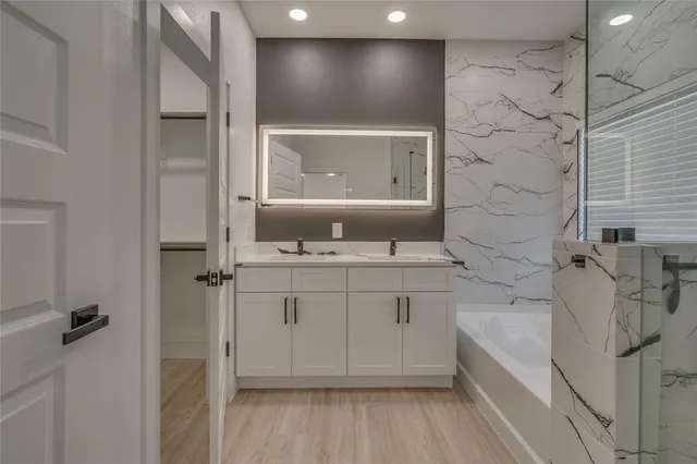 a spacious bathroom with a double vanity sink a mirror and a bathtub