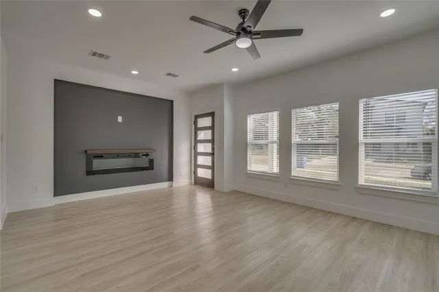 a view of an empty room with a window and kitchen view