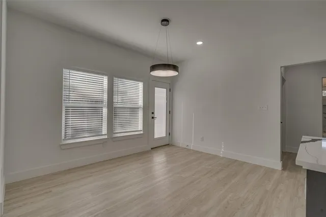 a view of an empty room with a window and wooden floor
