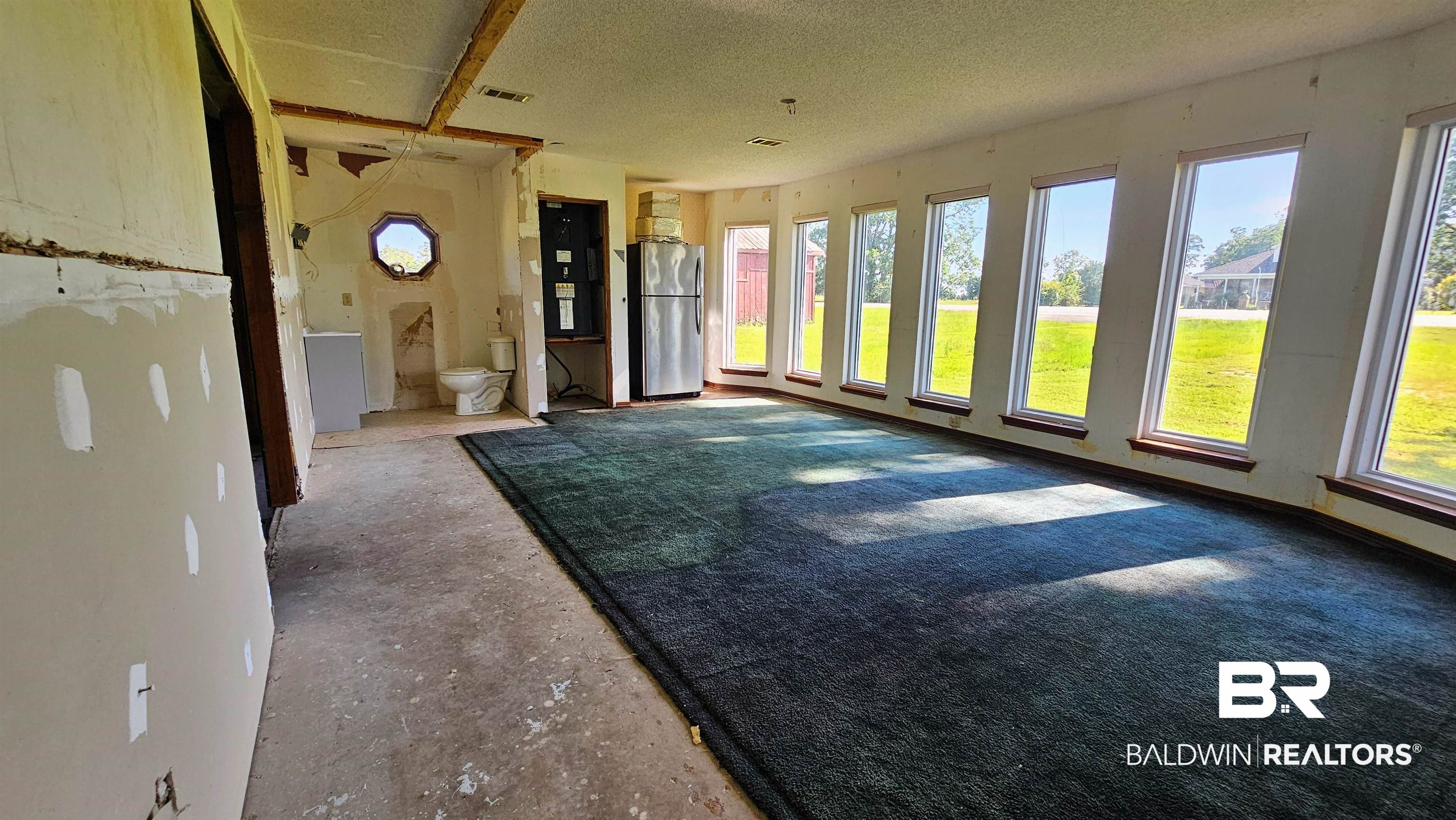 18824 Highway 41 Brewton, AL 36426 - Photo 14 of 40 Spacious interior featuring a series of tall windows, dark carpet flooring, and exposed ceiling beams