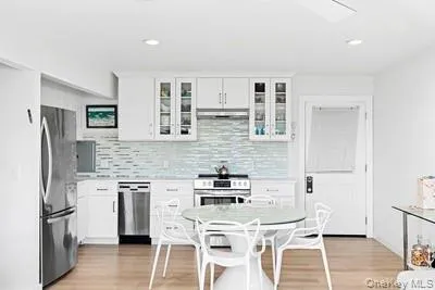 a kitchen with stainless steel appliances kitchen island a table chairs in it and wooden floors