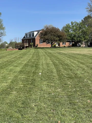 a view of a house with a big yard and large trees