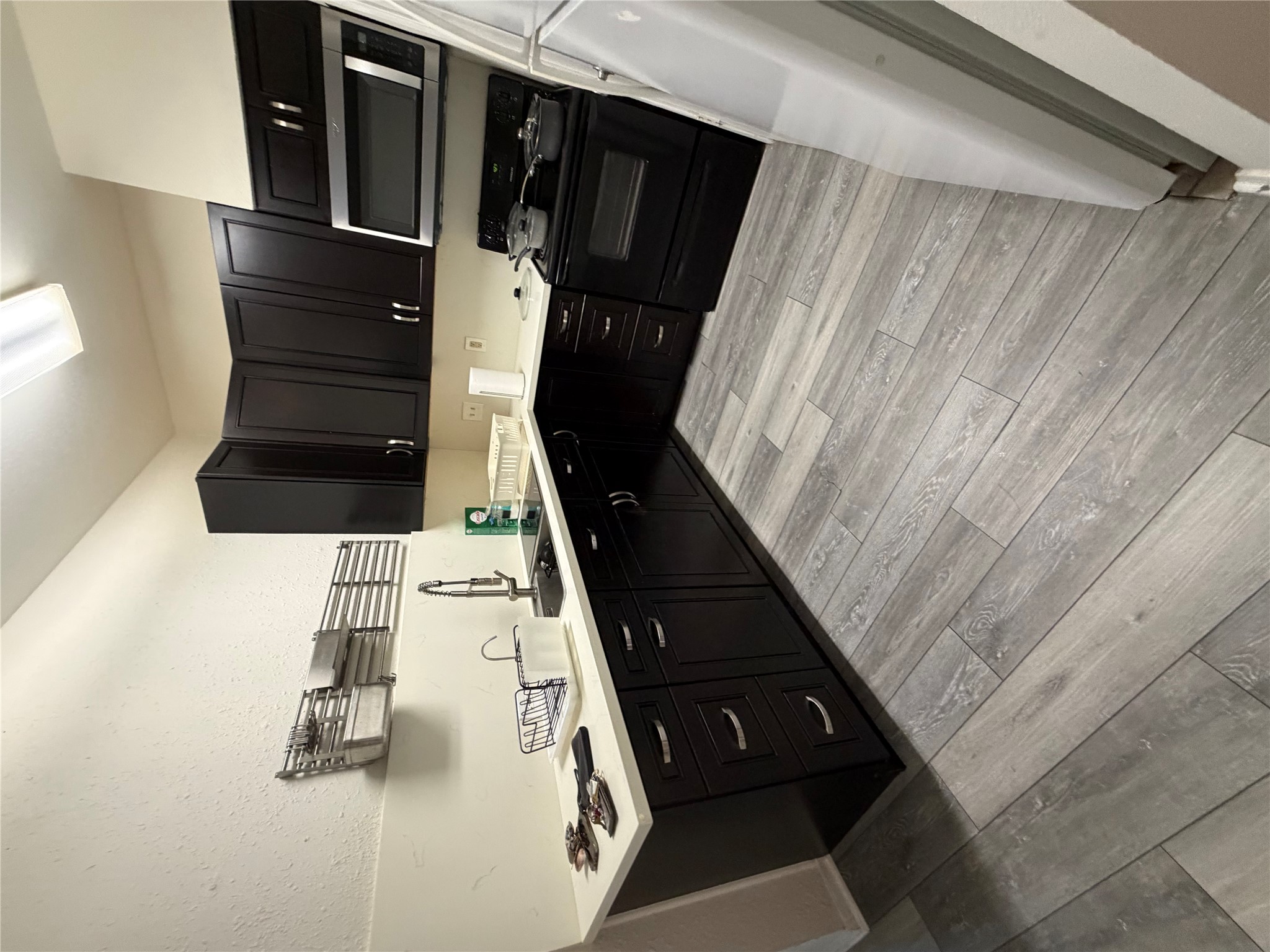 2801 Rio Grande Street, Unit 208 Austin, TX 78705 - Photo 3 of 8 A compact kitchen with sleek dark cabinetry and modern appliances perfect for urban living.