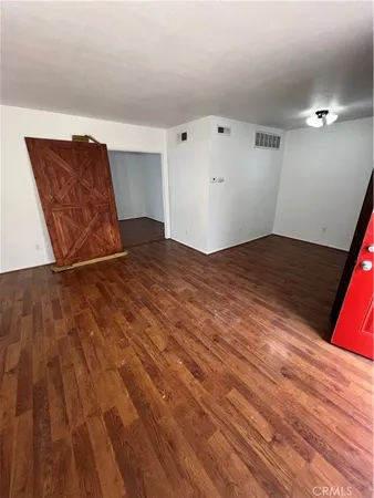 a view of an empty room with wooden floor and closet