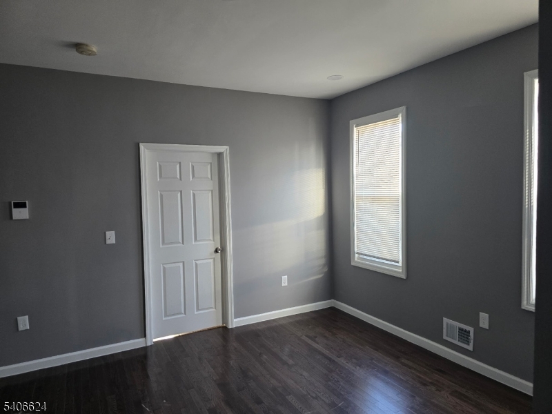 53 Aldine Street Newark, NJ 07112 - Photo 3 of 14 an empty room with wooden floor and windows