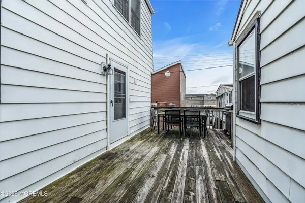 a view of a roof deck with table and chairs a barbeque with wooden floor and fence