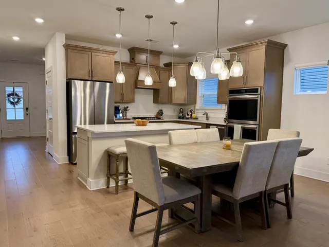 a kitchen with stainless steel appliances a dining table chairs refrigerator and microwave