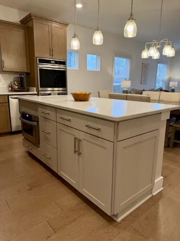 a kitchen with kitchen island granite countertop a sink a counter top space appliances and cabinets