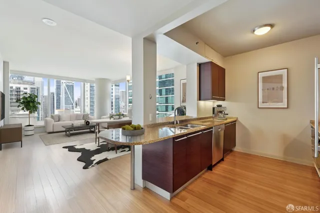 a large living room with stainless steel appliances granite countertop a couch wooden floor and a large window