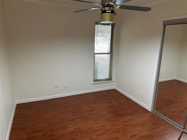 an empty room with wooden floor fan and windows