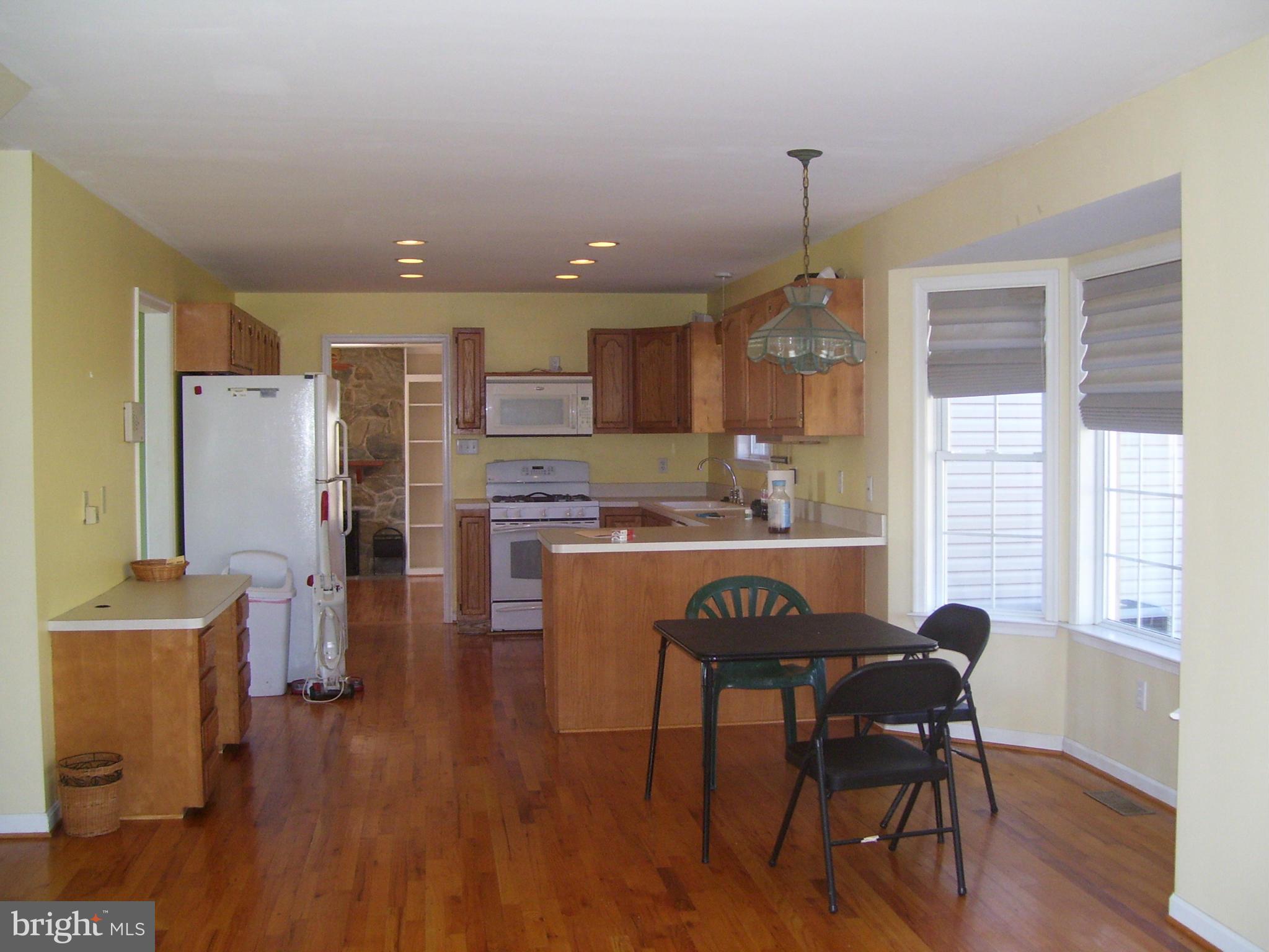 3311 Apple Pie Ridge Road Winchester, VA 22603 - Photo 12 of 23 a kitchen with stainless steel appliances granite countertop a stove top oven a refrigerator a dining table and chairs with wooden floor