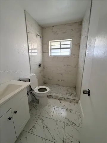 a bathroom with a sink a toilet a window and vanity