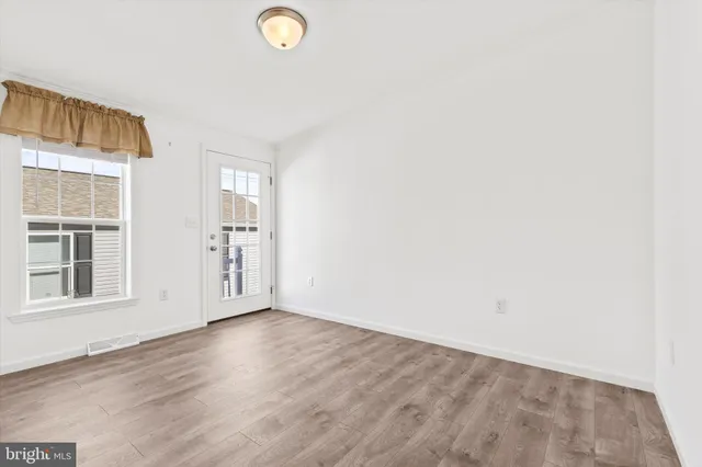 an empty room with wooden floor and windows