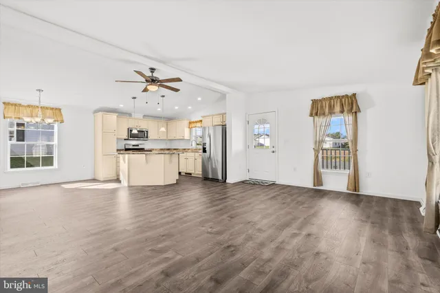 a view of an empty room with a kitchen and wooden floor