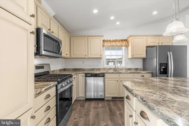 a kitchen with stainless steel appliances granite countertop a stove top oven a sink and a refrigerator