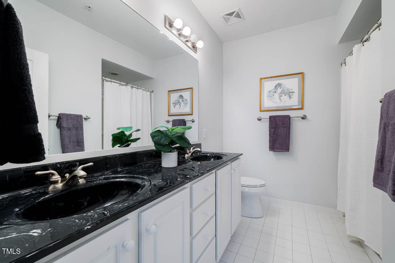 1221 Arborgate Circle, Unit 12 Chapel Hill, NC 27514 - Photo 12 of 20 a bathroom with a granite countertop sink a toilet a mirror and vanity