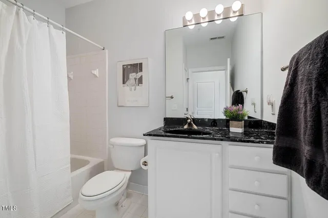 a bathroom with a granite countertop sink toilet and mirror
