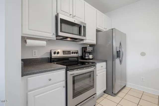a kitchen with stainless steel appliances granite countertop white cabinets a refrigerator and a stove top oven
