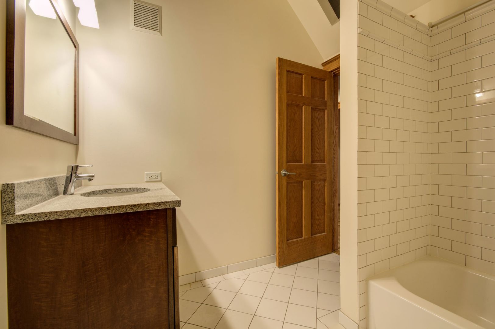 216 North May Street, Unit 303 Chicago, IL 60607 - Photo 17 of 19 a bathroom with a granite countertop sink and mirror with bathtub
