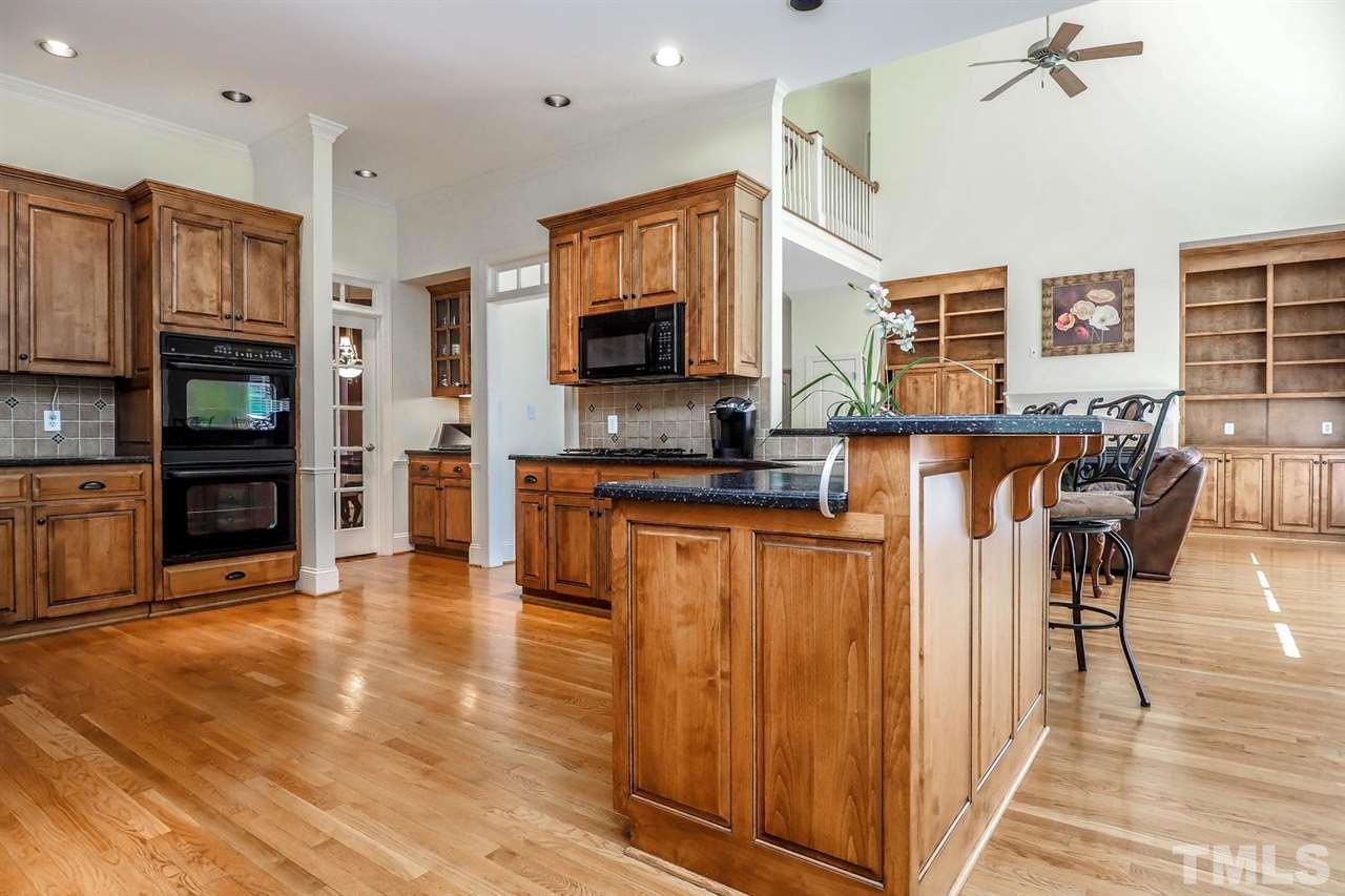 7017 Potomac Court Raleigh, NC 27613 - Photo 8 of 25 a kitchen with stainless steel appliances granite countertop a refrigerator a stove top oven and a dining table with wooden floor