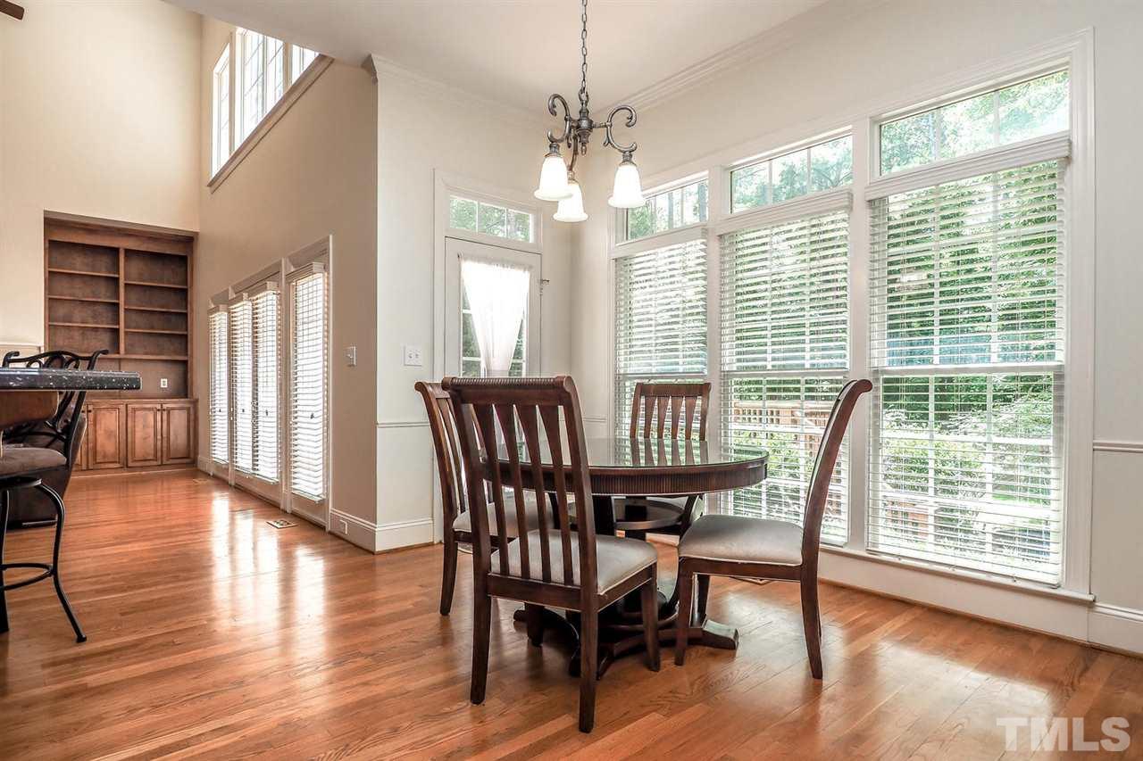 7017 Potomac Court Raleigh, NC 27613 - Photo 10 of 25 a dining room with wooden floor a chandelier a glass table and chairs