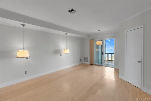 a view of an empty room with wooden floor and windows