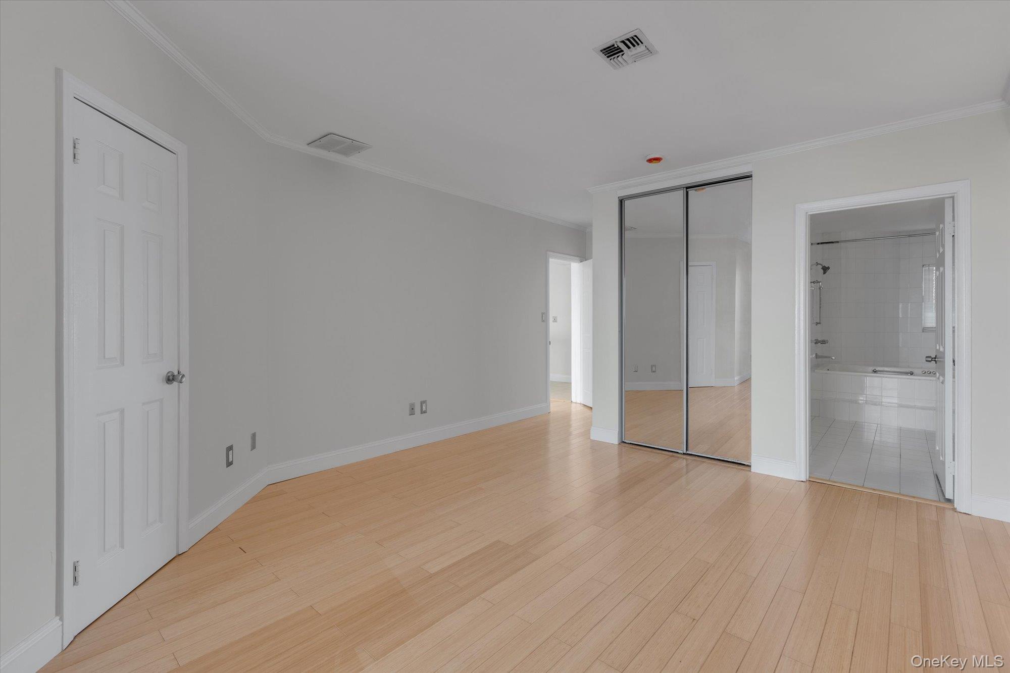 209 Fox Hill Drive Baiting Hollow, NY 11933 - Photo 13 of 28 Unfurnished bedroom featuring light wood-style flooring, connected bathroom, a closet, and ornamental molding