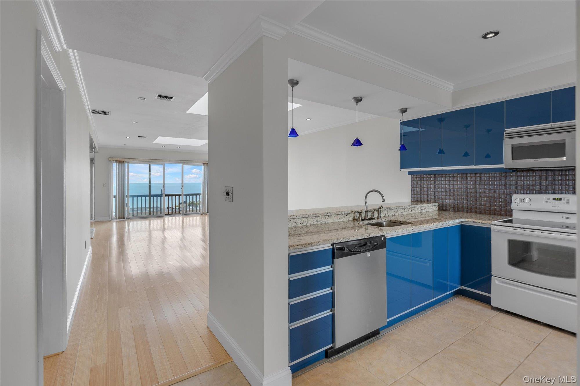 209 Fox Hill Drive Baiting Hollow, NY 11933 - Photo 7 of 28 Kitchen with blue cabinets, appliances with stainless steel finishes, tasteful backsplash, light stone counters, and pendant lighting