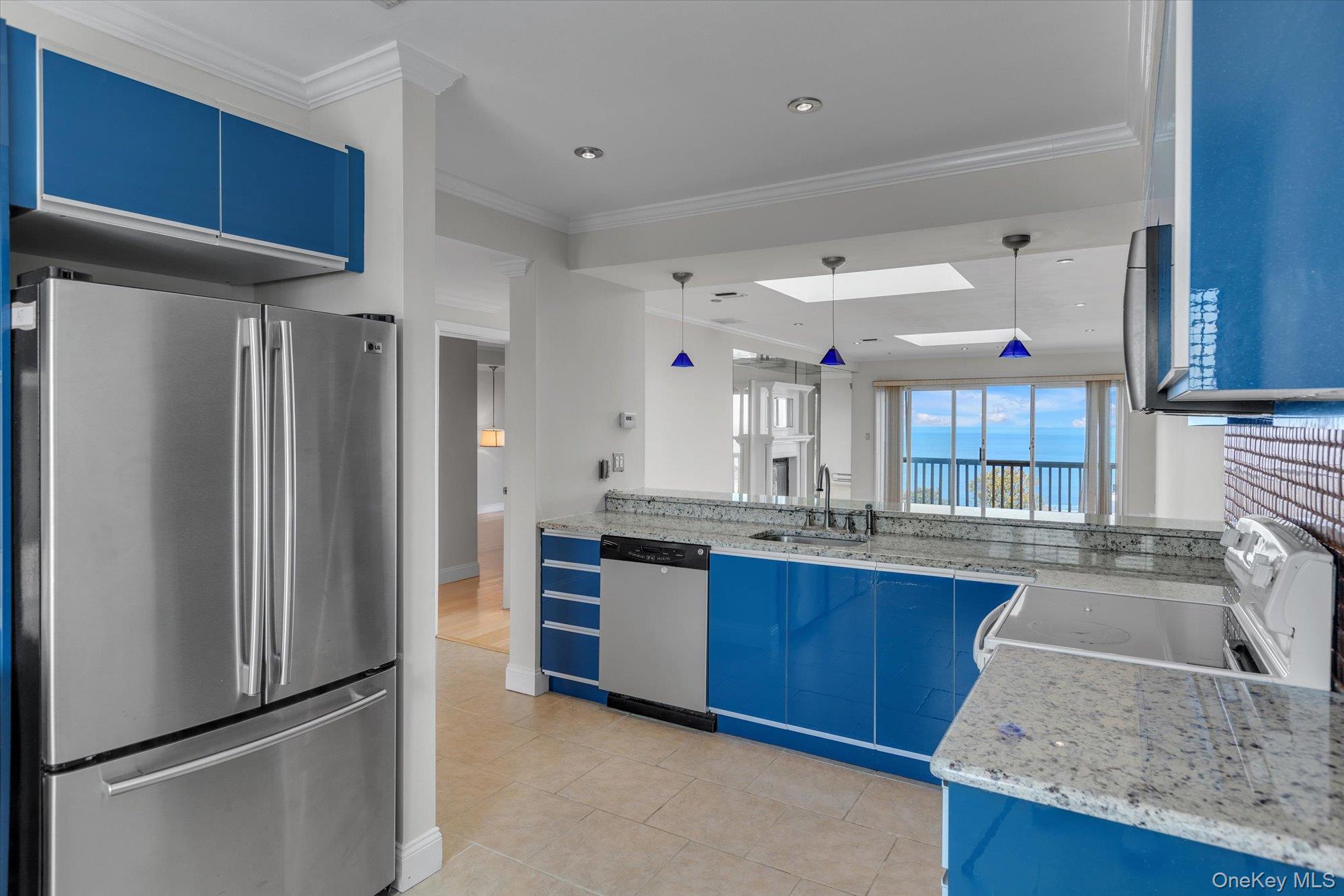 209 Fox Hill Drive Baiting Hollow, NY 11933 - Photo 9 of 28 Kitchen featuring blue cabinets, stainless steel appliances, ornamental molding, light stone countertops, and pendant lighting