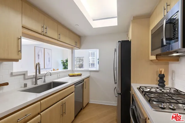 a kitchen with stainless steel appliances a sink a stove a microwave a refrigerator a sink and a refrigerator