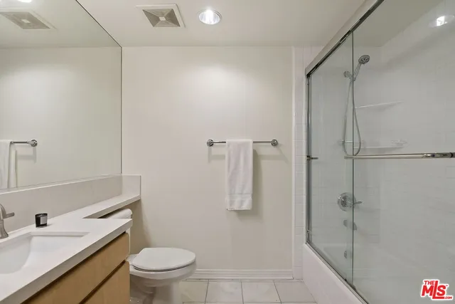 a bathroom with a granite countertop sink a toilet a mirror and shower