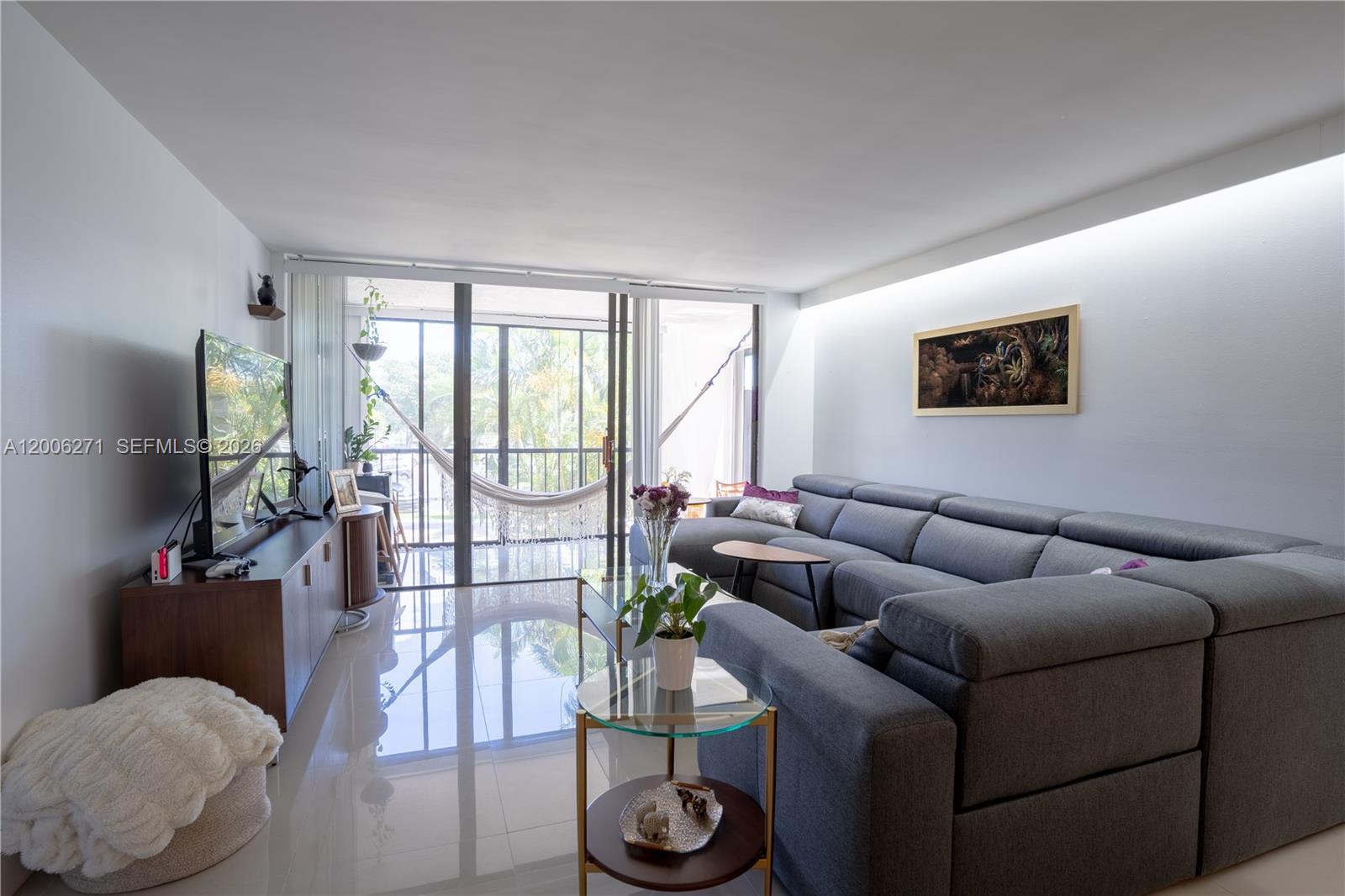 16300 Golf Club Road, Unit 204 Weston, FL 33326 - Photo 2 of 16 a living room with furniture a flat screen tv and a floor to ceiling window