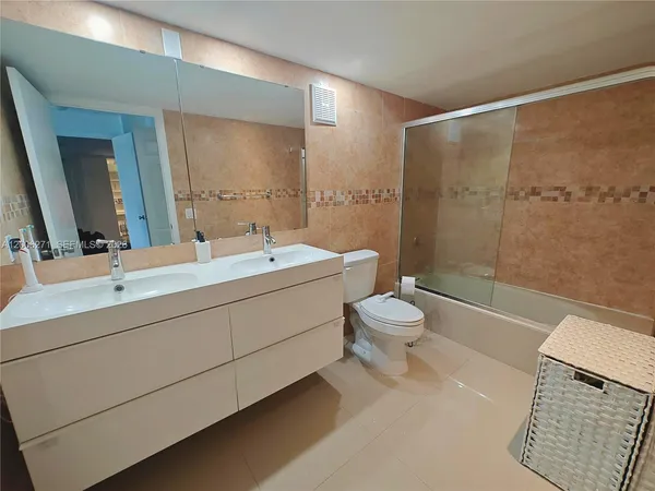 a bathroom with a double vanity sink toilet mirror and shower