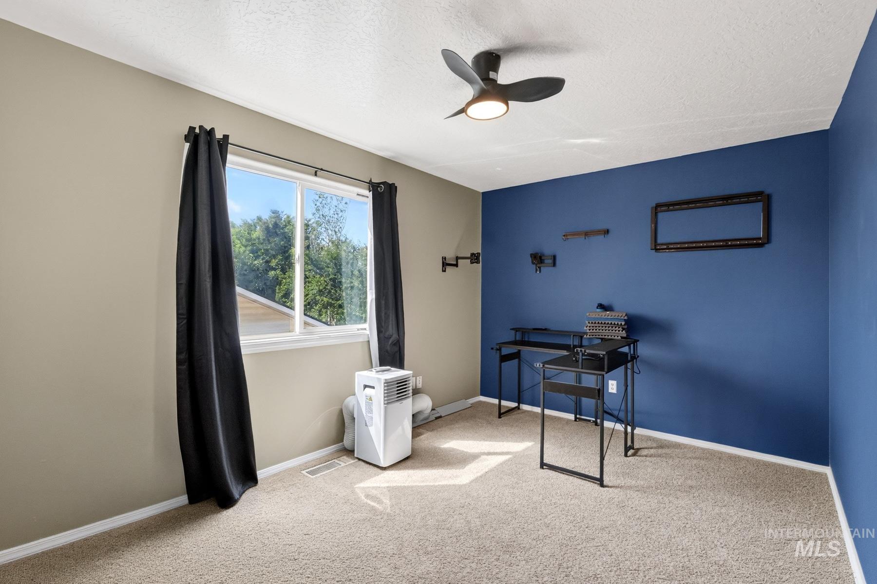 5020 Northrup Way Caldwell, ID 83607 - Photo 28 of 36 Carpeted room featuring a ceiling fan, a window with exterior views, and a two-tone wall treatment