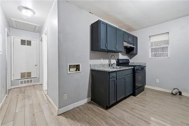 a kitchen with stainless steel appliances granite countertop a refrigerator a sink dishwasher and wooden cabinets with wooden floor