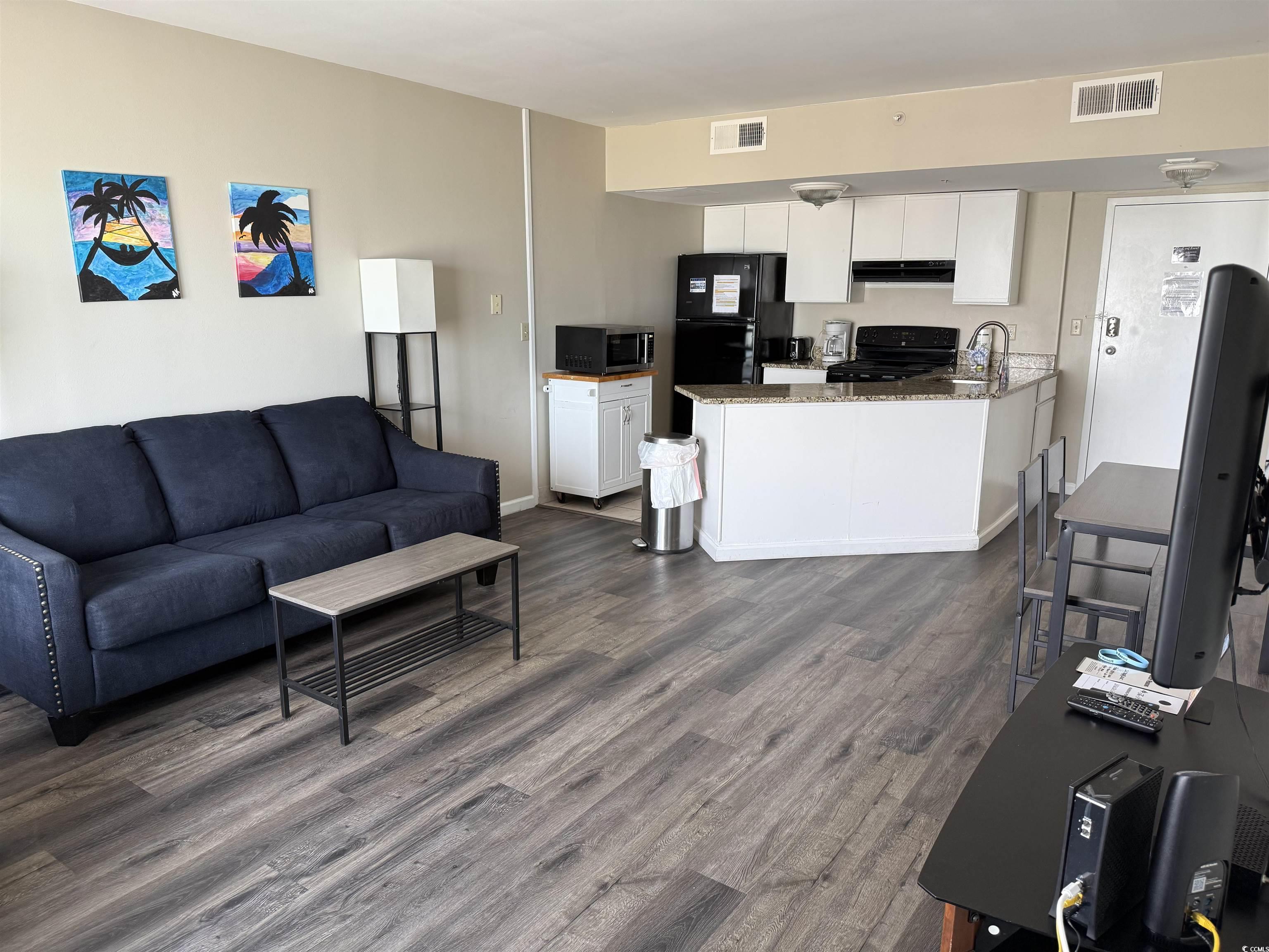 1605 South Ocean Boulevard, Unit 1211 Myrtle Beach, SC 29577 - Photo 7 of 22 Kitchen with black appliances, light tile patterned flooring, a peninsula, white cabinetry, and exhaust hood
