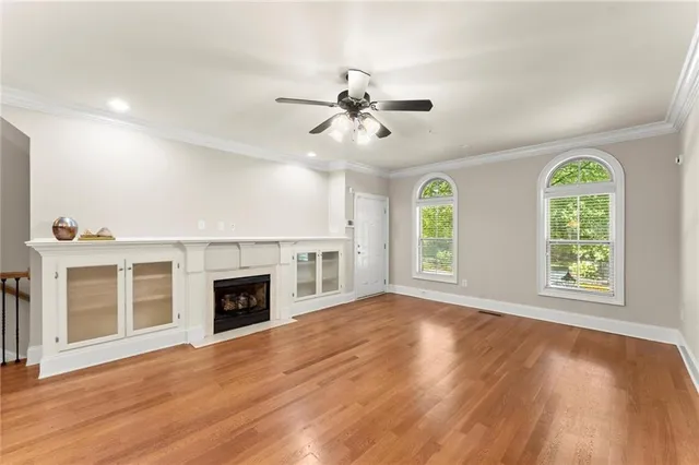 an empty room with windows fireplace and a ceiling fan