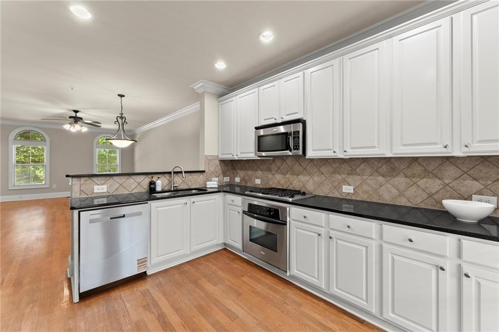6468 Chariot Street, Unit 19 Atlanta, GA 30328 - Photo 14 of 43 a kitchen with stainless steel appliances granite countertop a sink and cabinets with wooden floors