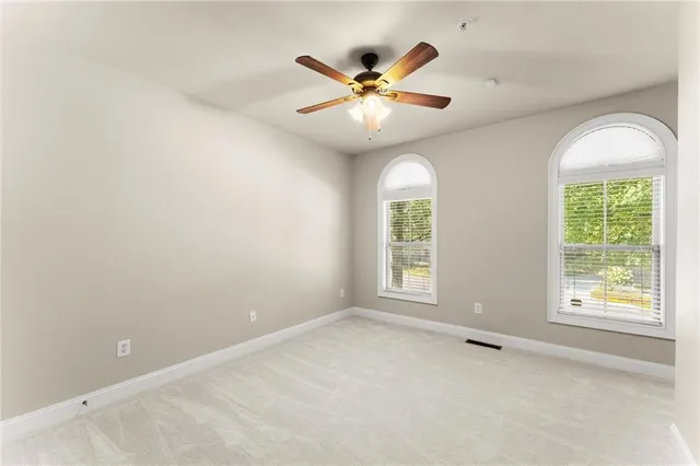 an empty room with windows and fan