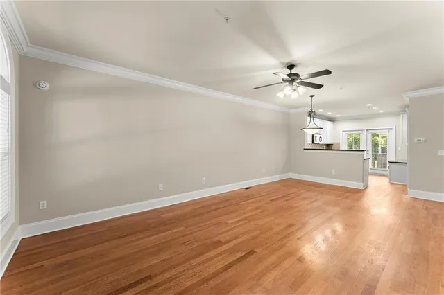 a view of an empty room with a chandelier fan and wooden floor