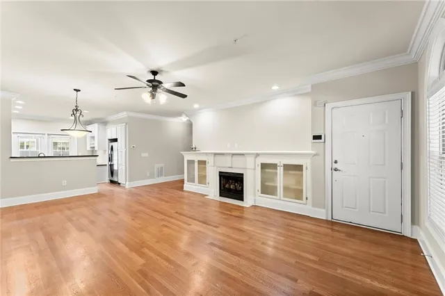 a view of a livingroom with a fireplace a ceiling fan and wooden floor