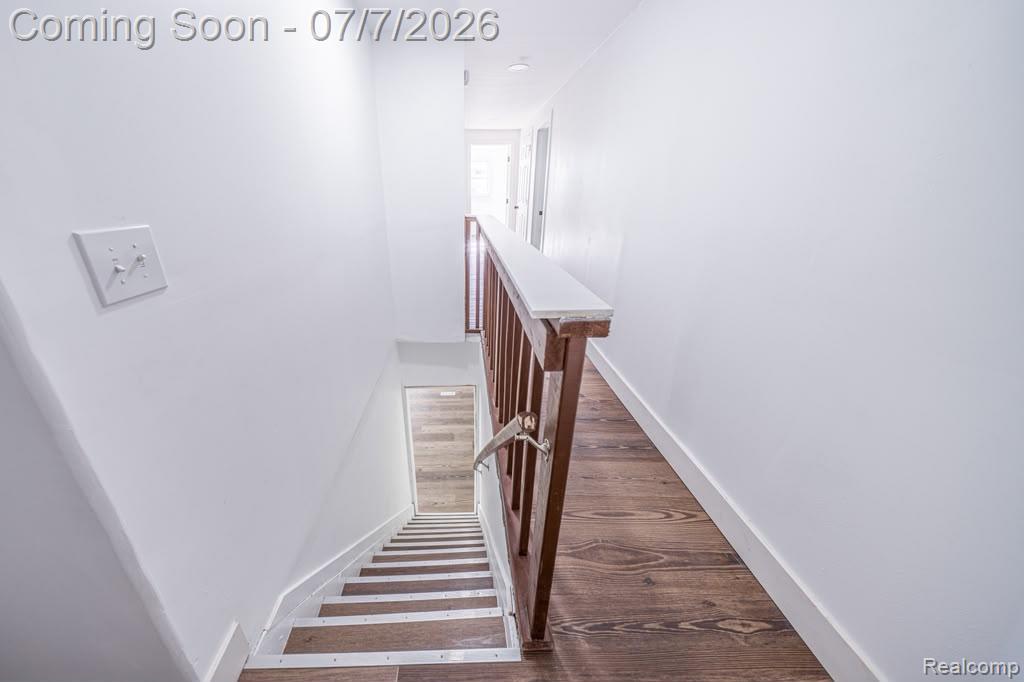 18486 Trinity Street Detroit, MI 48219 - Photo 11 of 19 Upper-level hallway featuring wood-finish flooring, white walls, and a staircase with a wood railing leading to a lower level