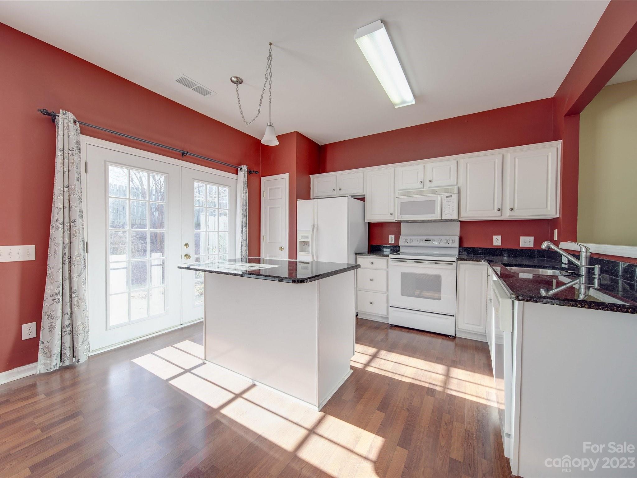 11755 Huxley Road Charlotte, NC 28277 - Photo 11 of 37 a kitchen with stainless steel appliances kitchen island granite countertop a stove a sink and white cabinets with wooden floor