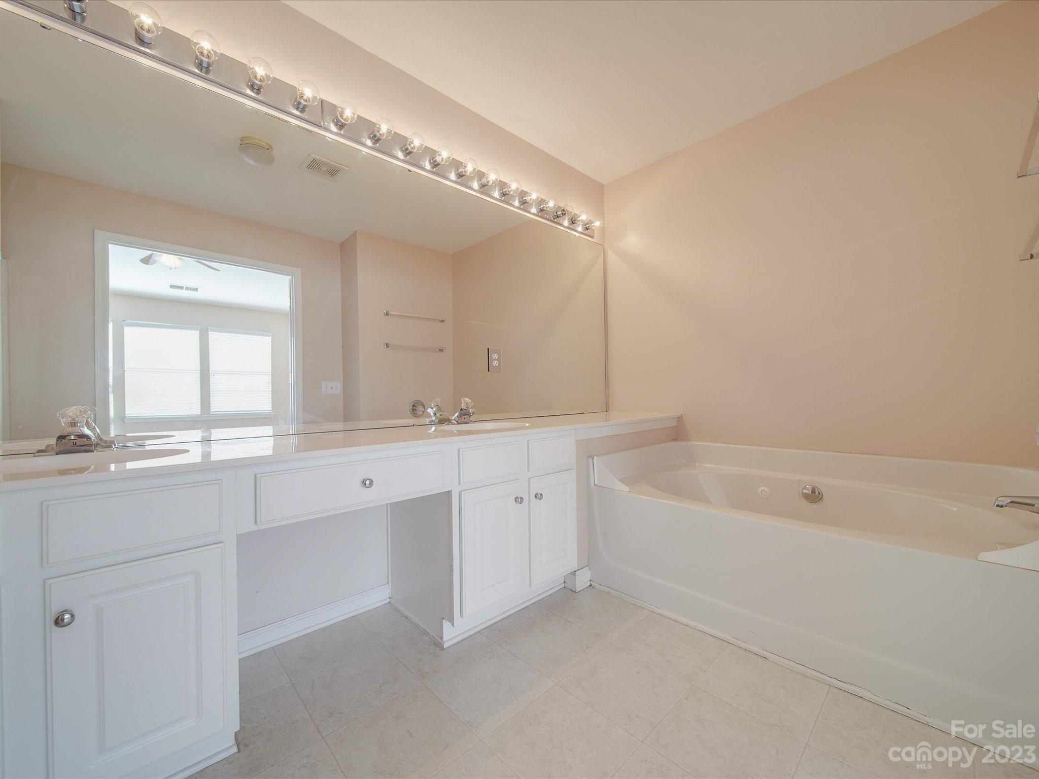 11755 Huxley Road Charlotte, NC 28277 - Photo 29 of 37 a spacious bathroom with a double vanity sink a mirror and a bathtub