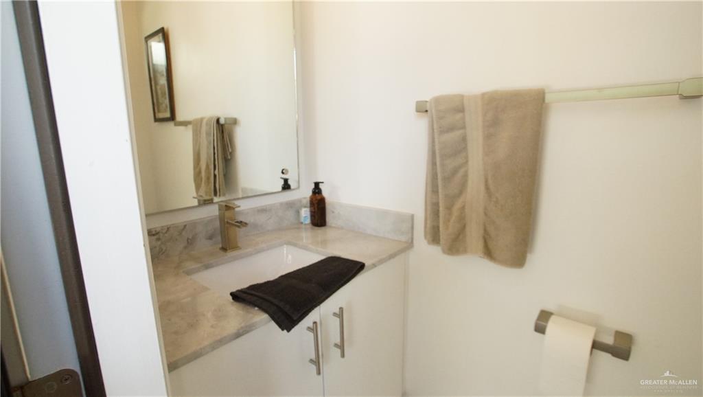 414 Ric Mar Street Edinburg, TX 78541 - Photo 36 of 36 Vanity with a rectangular undermount sink, light-toned stone countertop, and contemporary gold-toned faucet