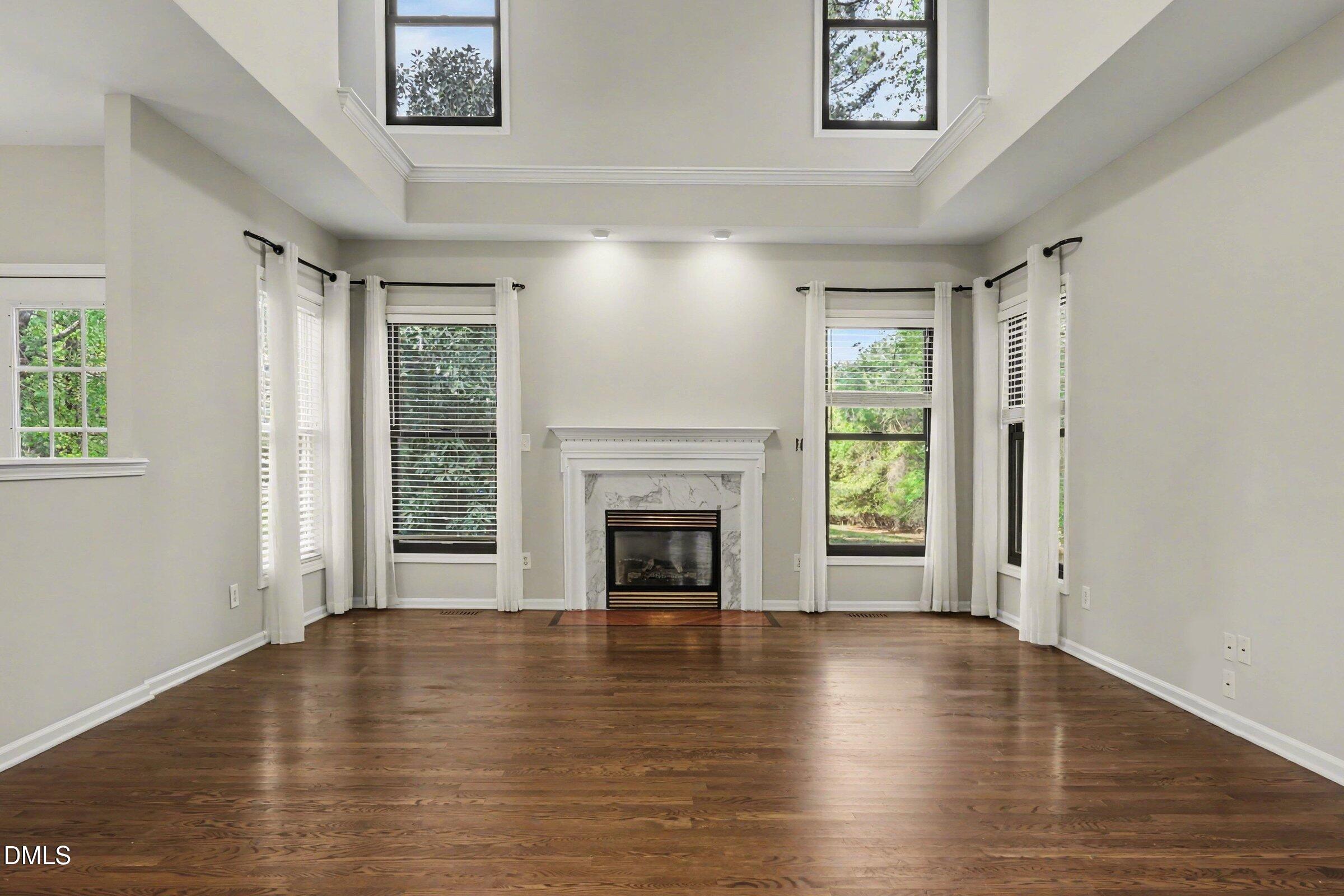 1001 Denfield Court Raleigh, NC 27615 - Photo 13 of 44 a view of a livingroom with wooden floor a fireplace and windows