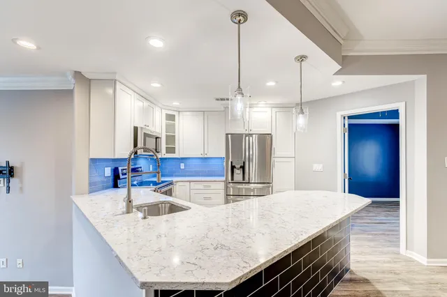 a kitchen with kitchen island granite countertop a sink a refrigerator and chairs