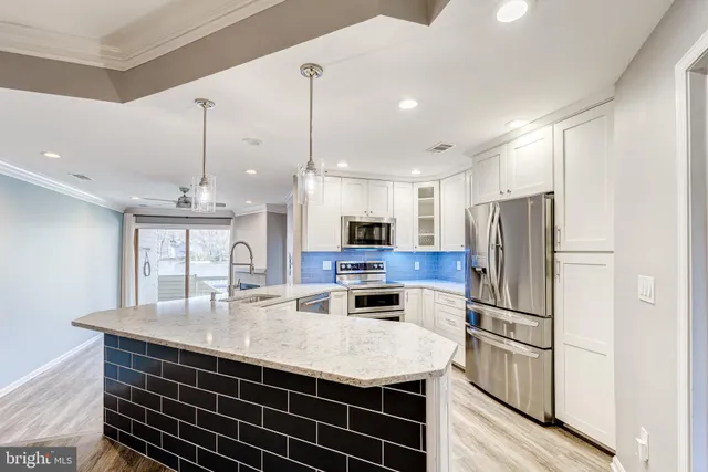 a kitchen with stainless steel appliances a sink a refrigerator a center island a stove and a sink