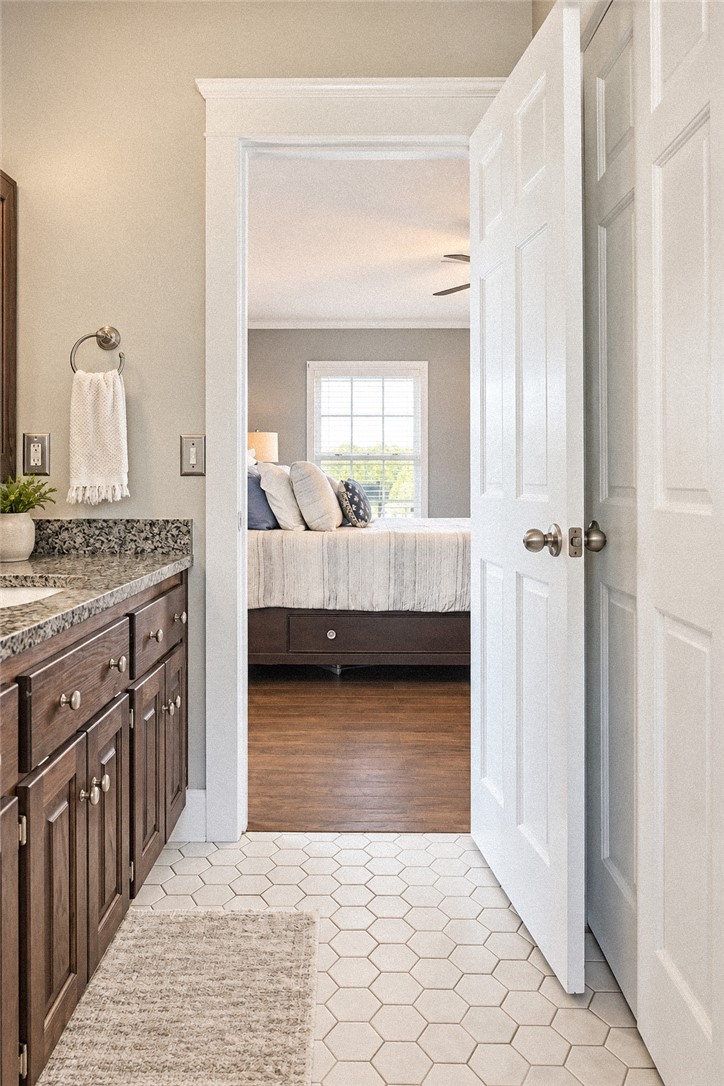 2420 Rainey Road Starr, SC 29684 - Photo 18 of 36 A spacious doorway connects the bathroom, featuring stone counters and tile floors, directly to the bedroom.